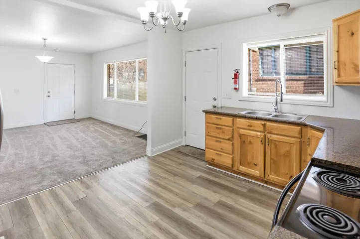 Kitchen with range with electric cooktop, a chandelier, and light wood-type flooring