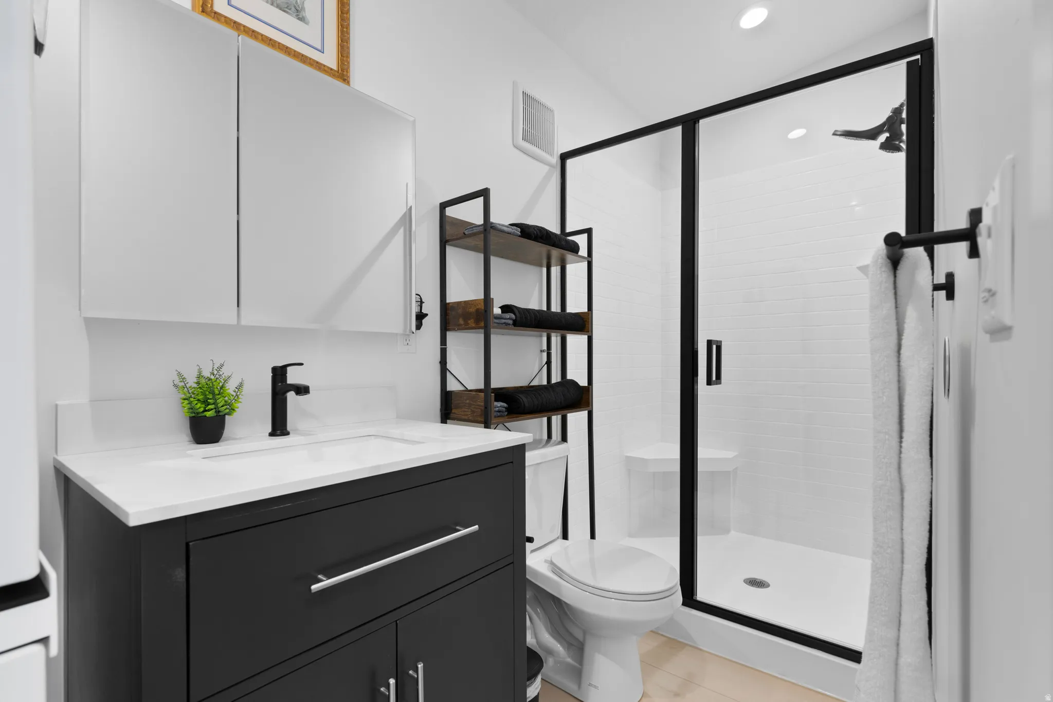 Full bath with vanity, a stall shower, and stacked washer/dryer