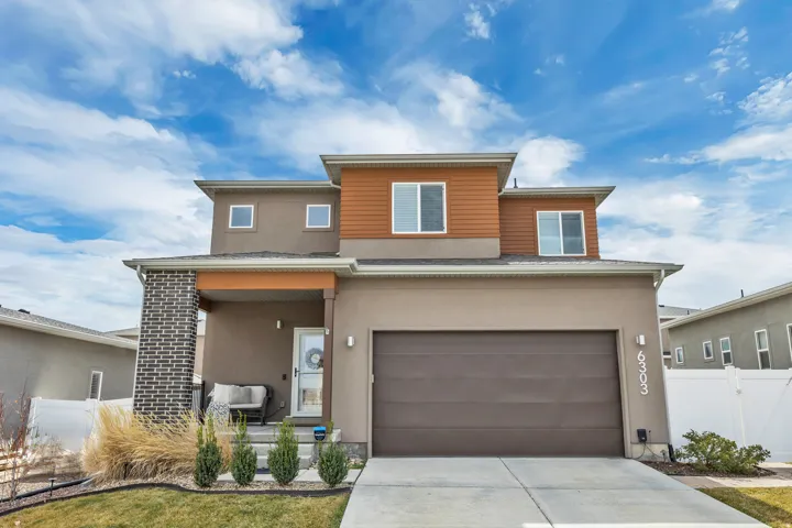 Prairie-style home featuring stucco siding, a porch, concrete driveway, and an attached garage