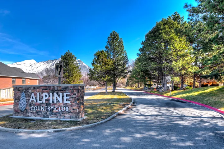 Community sign featuring a mountain view and a lawn