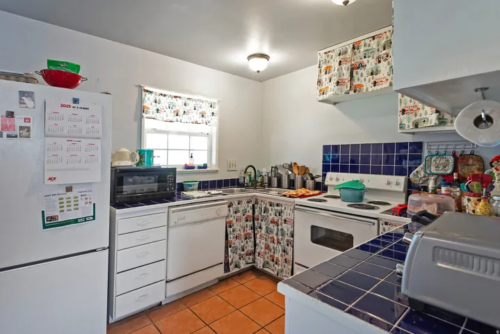 Kitchen with tile counters, white appliances, white cabinetry, light tile patterned floors, and tasteful backsplash