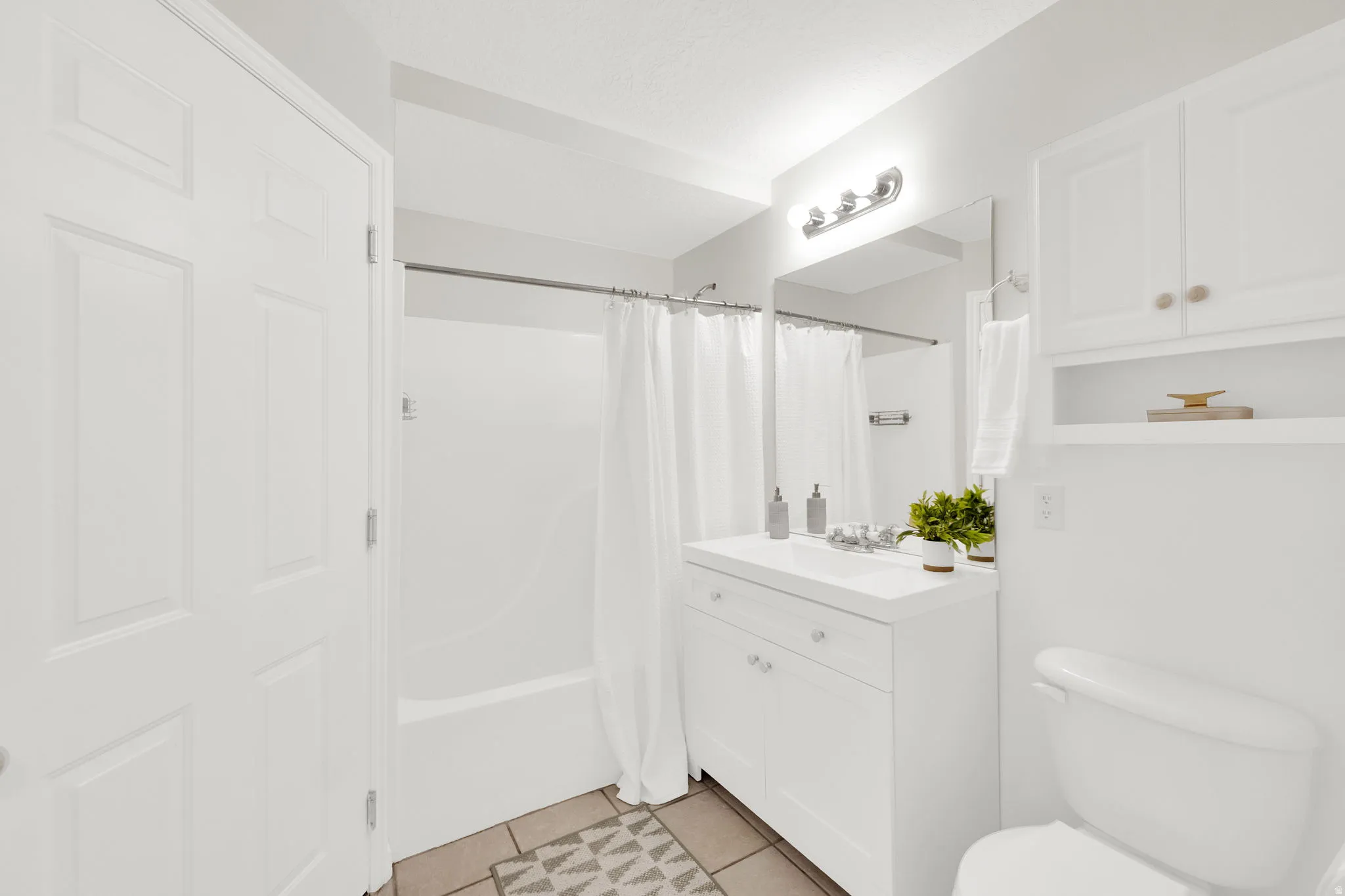 Full bath featuring vanity, shower / tub combo with curtain, and light tile patterned floors