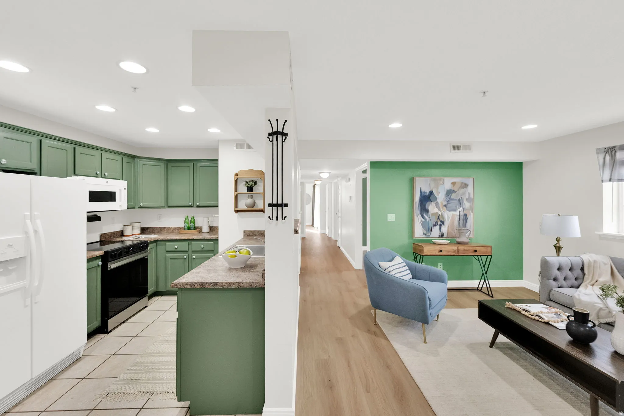 Kitchen with green cabinetry, white appliances, open floor plan, light countertops, and recessed lighting