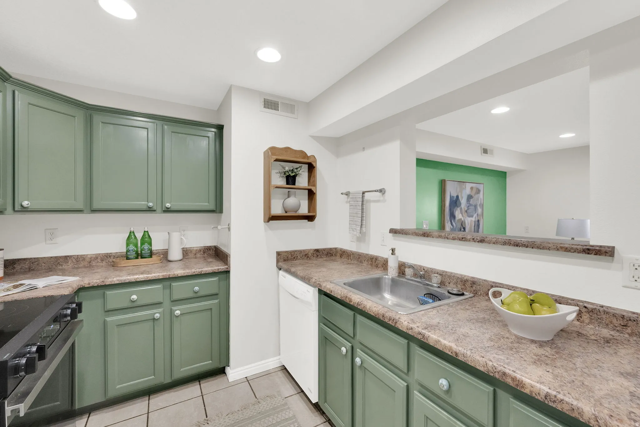 Kitchen featuring green cabinets, electric stove, dishwasher, light tile patterned floors, and light countertops