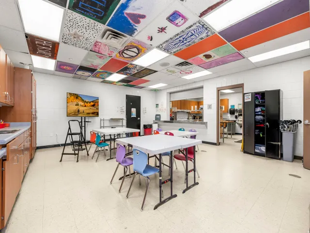 Dining area featuring light floors, concrete block wall, and a paneled ceiling