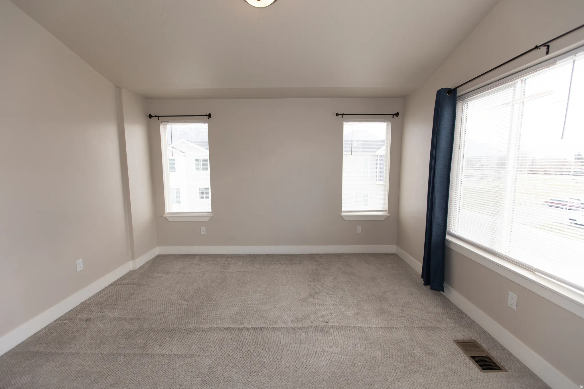 Empty room with light colored carpet and plenty of natural light