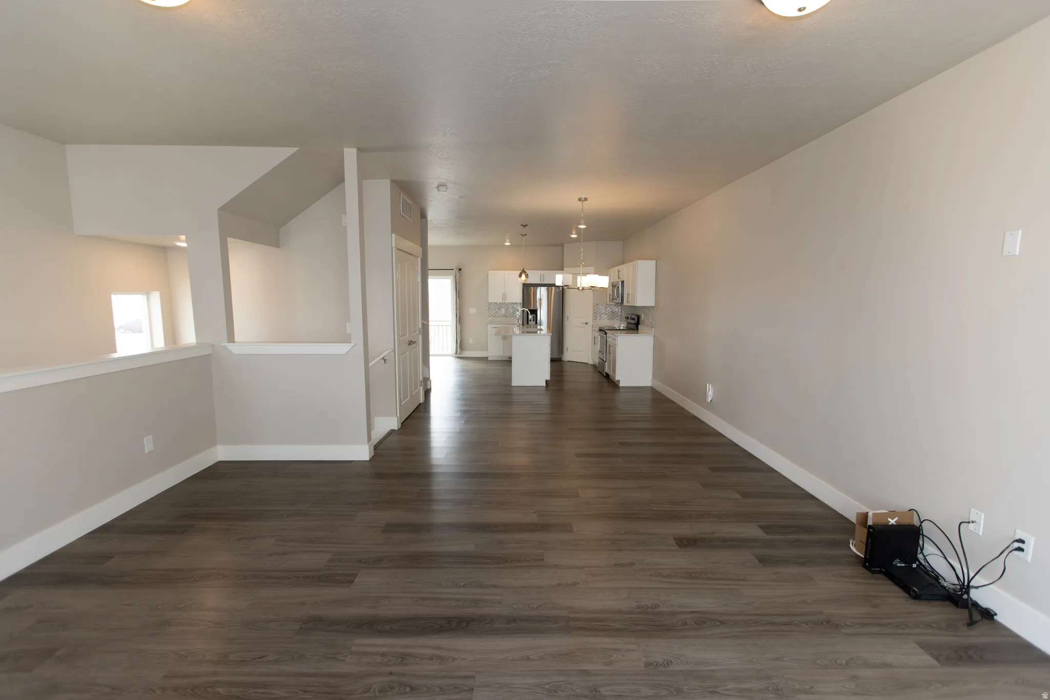 Unfurnished living room with dark wood-style floors and baseboards