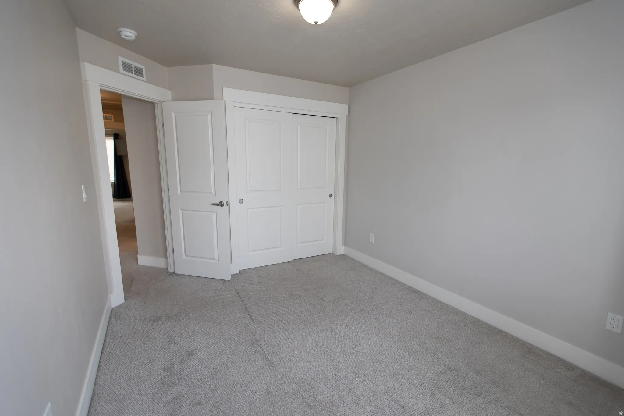 Unfurnished bedroom featuring light colored carpet and a closet