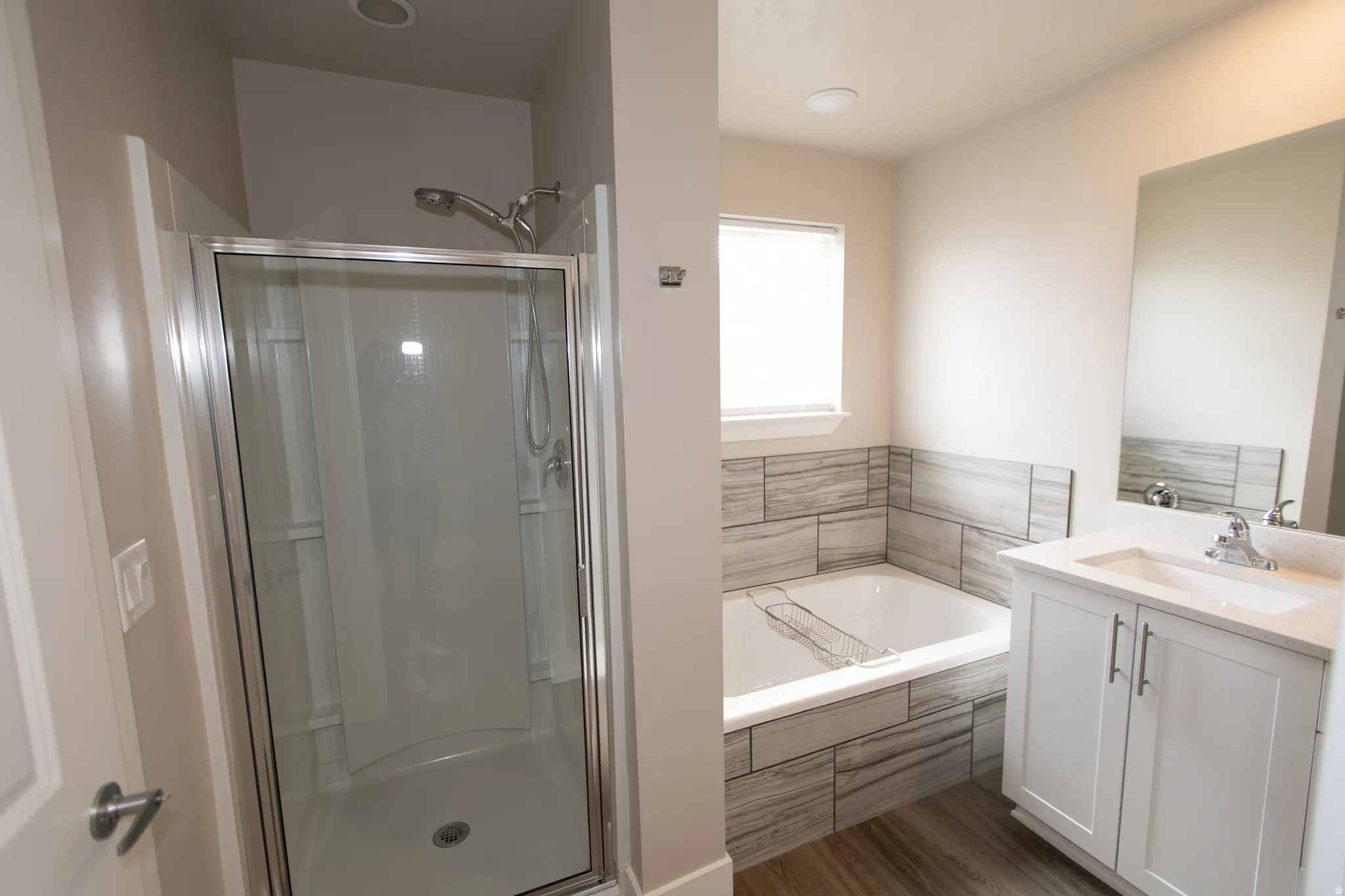 Bathroom featuring vanity, a garden tub, dark wood finished floors, and a stall shower