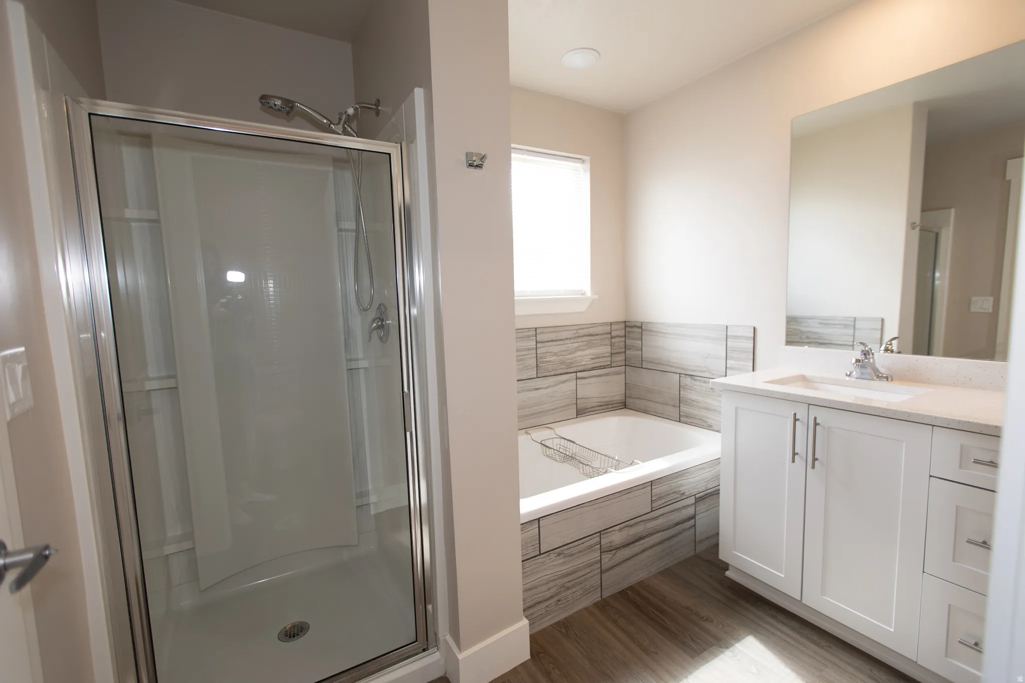 Bathroom featuring vanity, a stall shower, a bath, and light wood-style floors