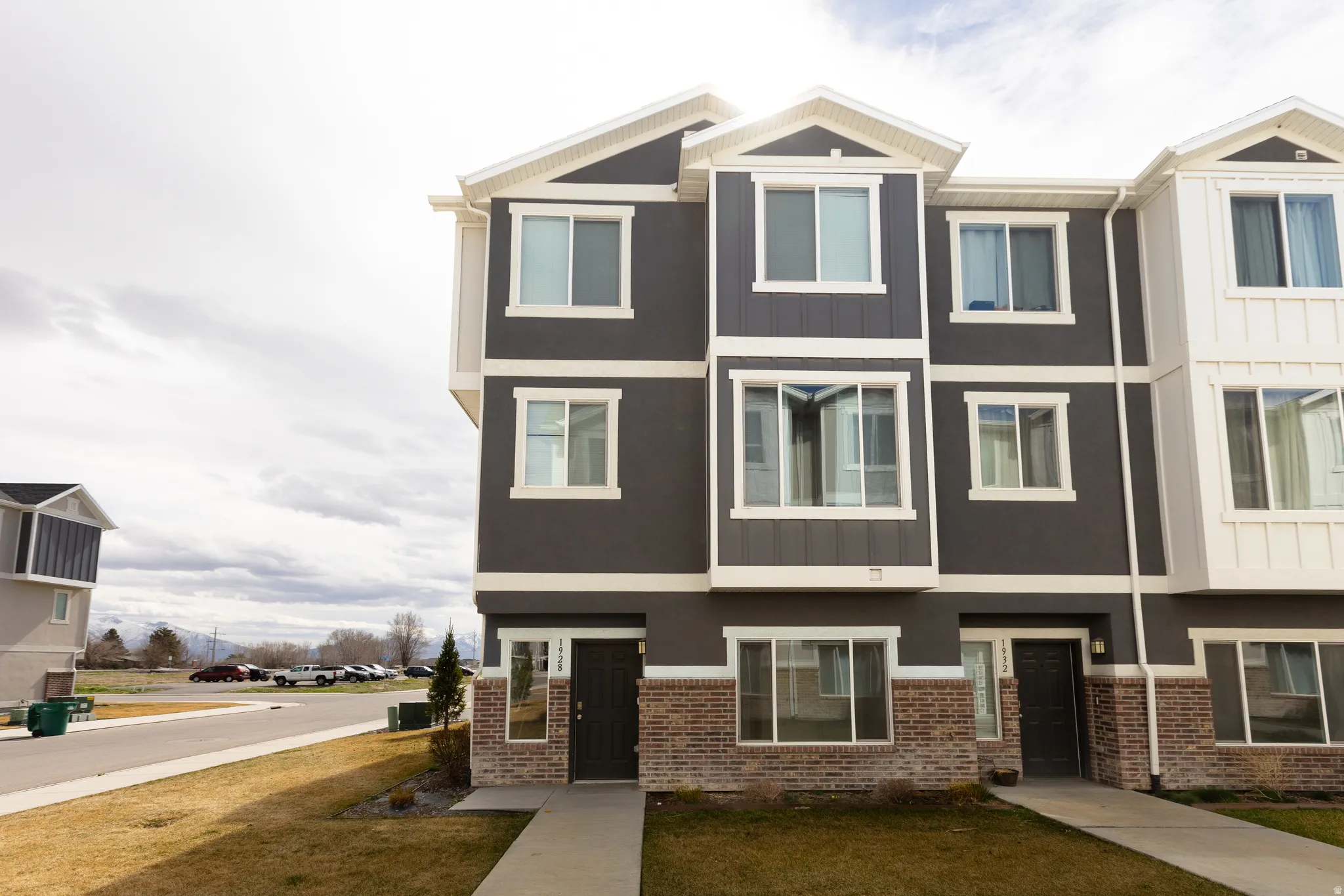 View of front of house featuring brick siding, a front lawn, stucco siding, and board and batten siding
