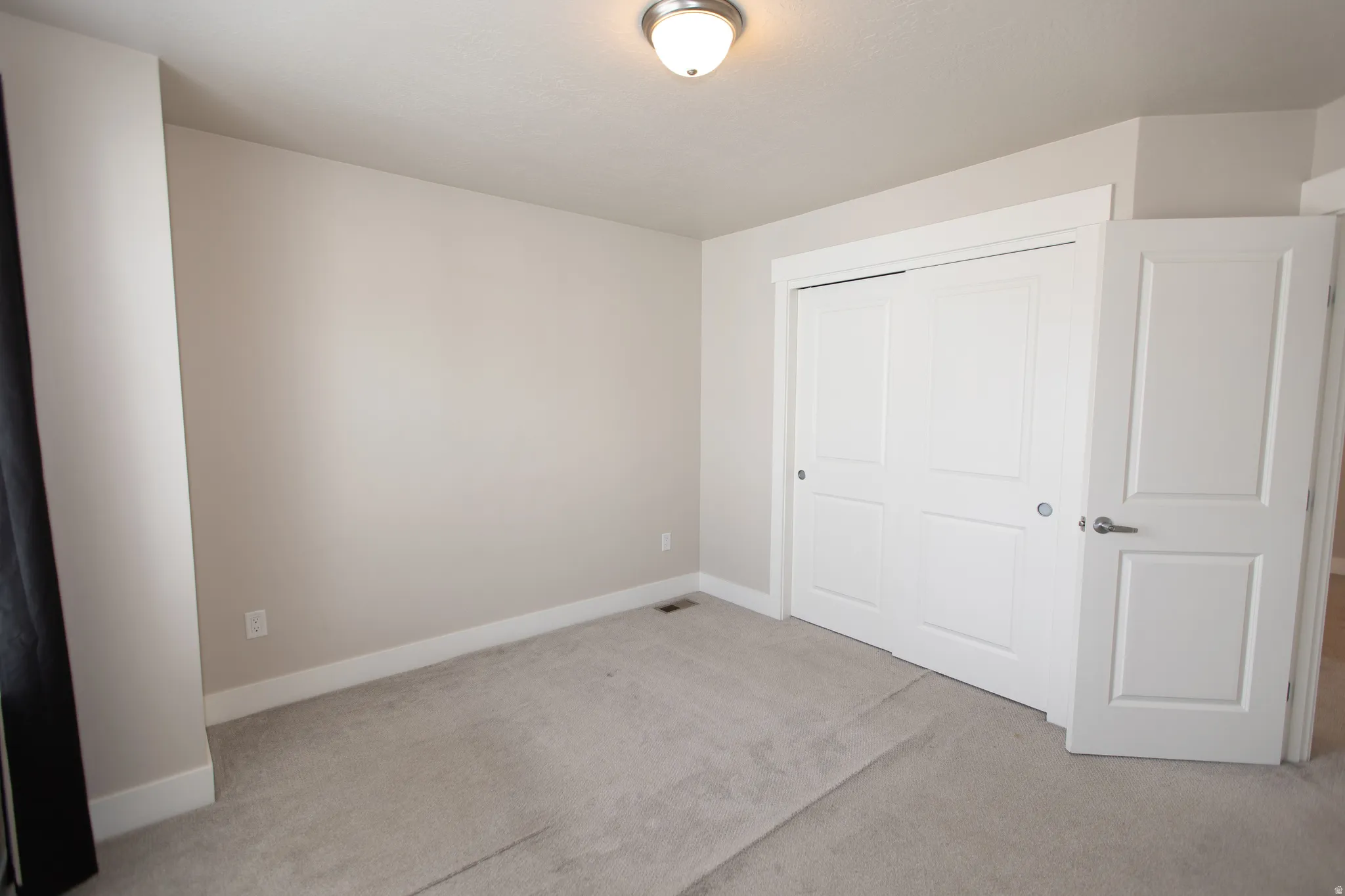 Unfurnished bedroom with light carpet and a closet