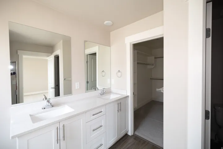 Dual vanity with undermount sinks, white cabinetry, chrome fixtures, and a light-toned countertop