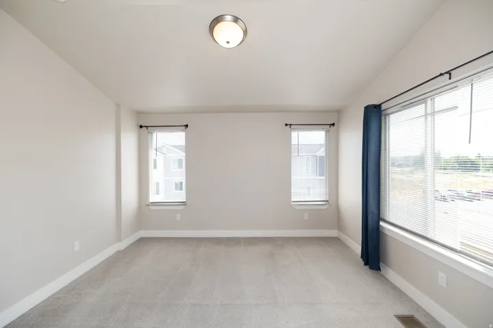 Neutral wall color with plush carpeting, illuminated by a ceiling-mounted light fixture