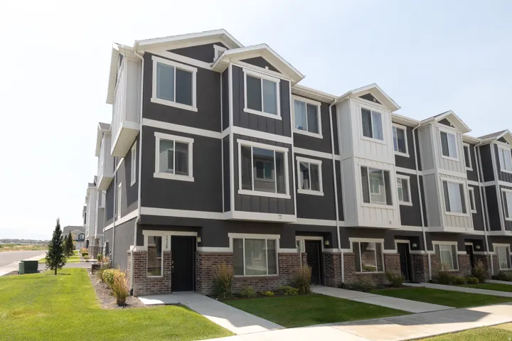 Multi-level townhome featuring dark gray siding, white trim, and a brick-look facade