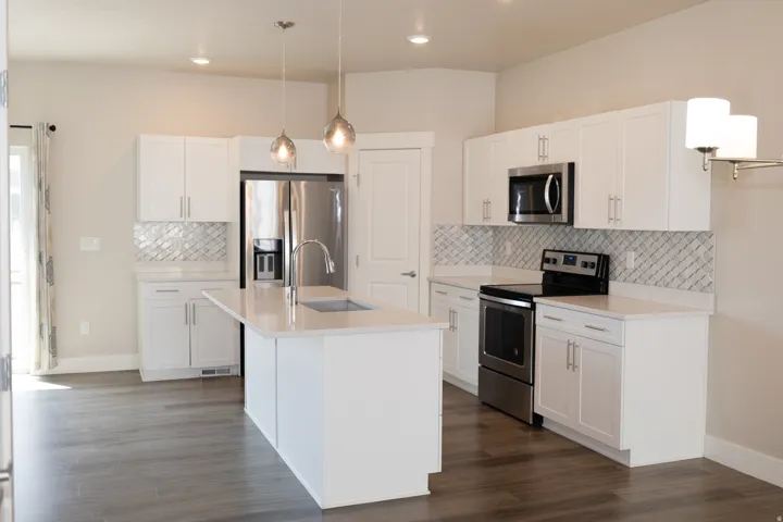 Modern kitchen featuring white cabinetry, stainless steel appliances, a center island with sink, and wood-finish flooring