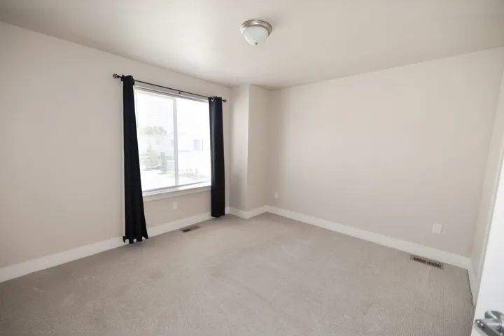 Neutral-toned walls, light-colored carpet, and a large window