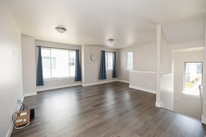 Spacious room featuring wood-finish flooring, multiple windows, and a neutral color palette