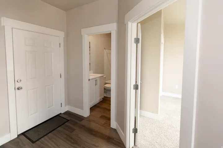 Wood-finish flooring, white paneled door, and neutral wall tones