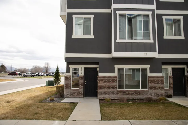 View of front of home with brick siding, board and batten siding, stucco siding, and a front lawn