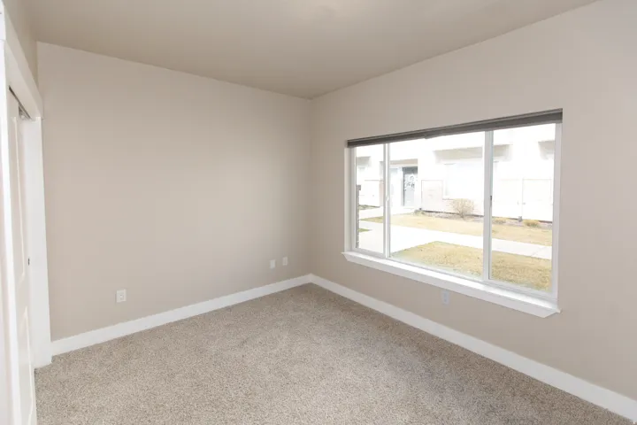 Expansive window with white trim, neutral-toned walls, and plush carpet flooring