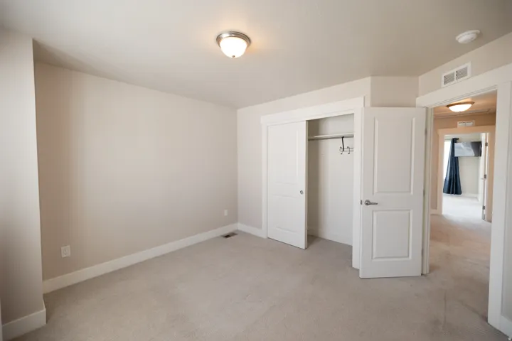 Neutral wall paint, plush carpeting, ceiling-mounted light fixture, and closet with bi-fold doors