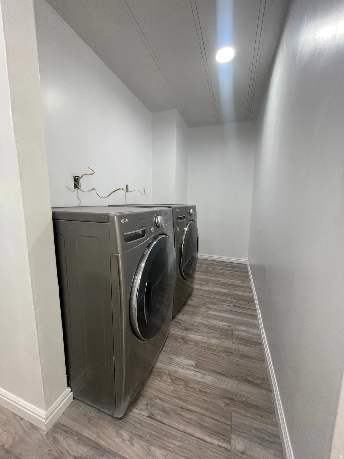 Laundry area featuring light wood-type flooring, washer and clothes dryer, and recessed lighting