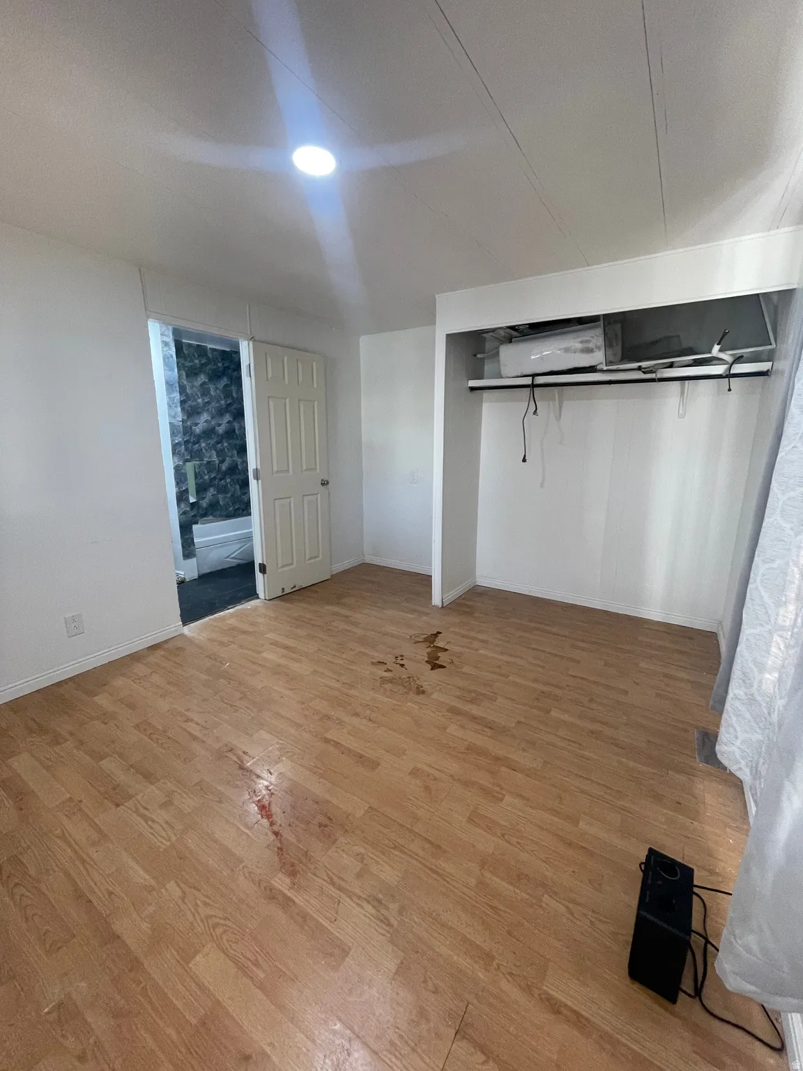Unfurnished bedroom featuring light wood-style floors, connected bathroom, and a closet