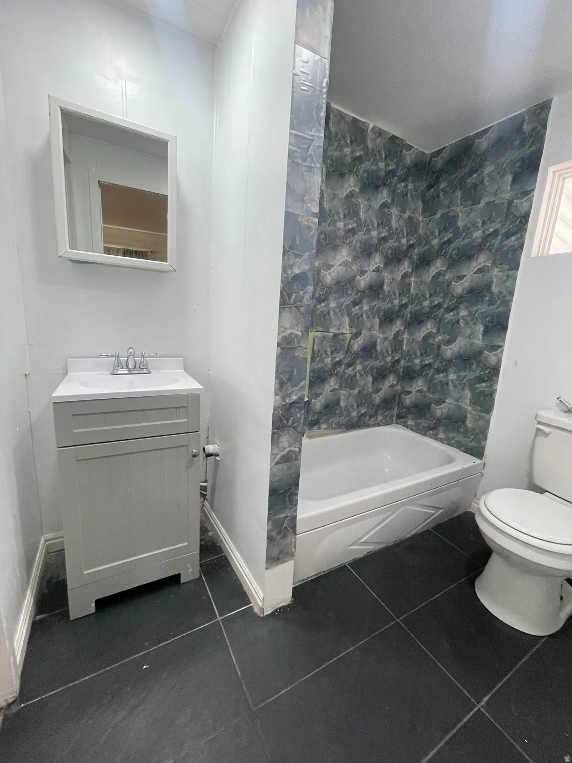 Full bath featuring vanity and dark tile patterned flooring