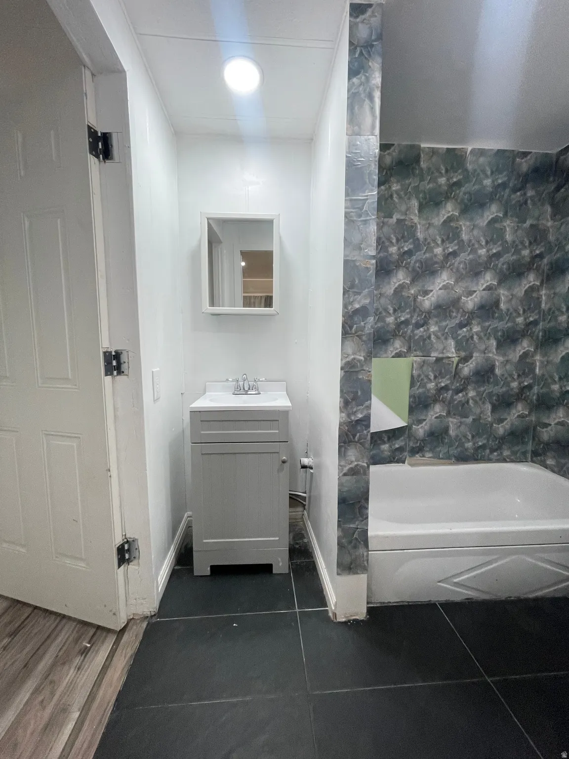 Full bath with vanity, a tub to relax in, and dark tile patterned flooring