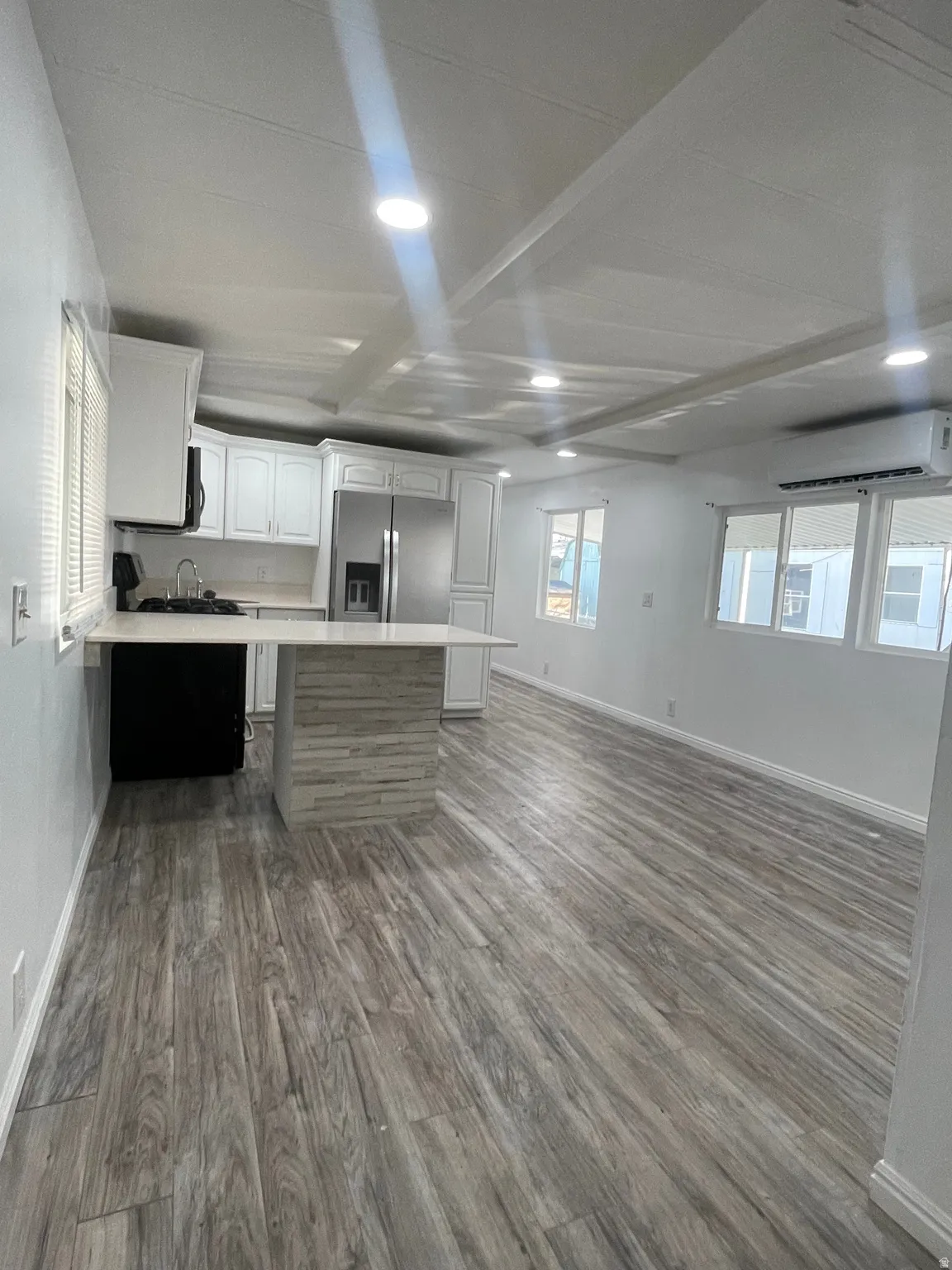 Two tone kitchen featuring light countertops, stainless steel appliances, dual tone cabinetry, open floor plan, and dark wood-style floors