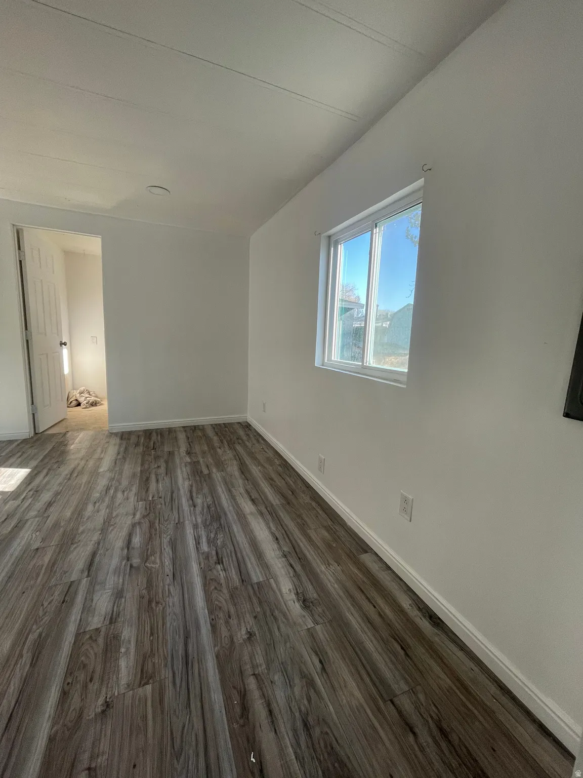 Empty room with dark wood-type flooring and baseboards