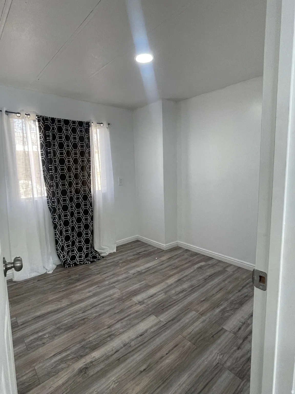 Empty room featuring dark wood-type flooring and healthy amount of natural light