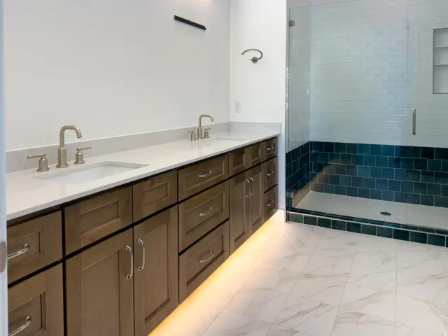 Full bath featuring double vanity, a stall shower, and light marble finish flooring