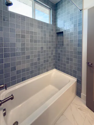 Bathroom with bathtub / shower combination and light marble finish flooring