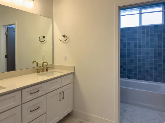 Bathroom with double vanity, light marble finish flooring, and tub / shower combination