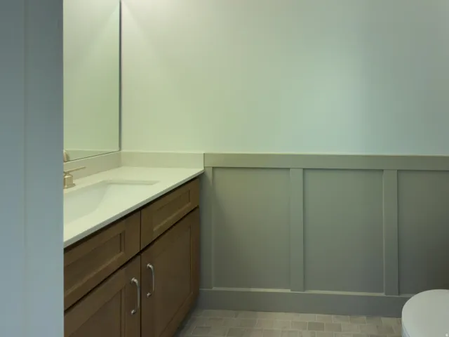 Half bathroom with a decorative wall, vanity, and wainscoting