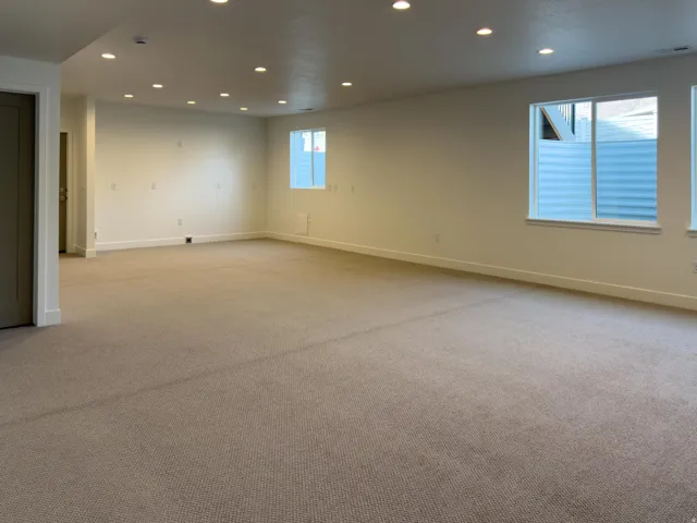Empty room featuring recessed lighting and light carpet stubbed for a kitchen.