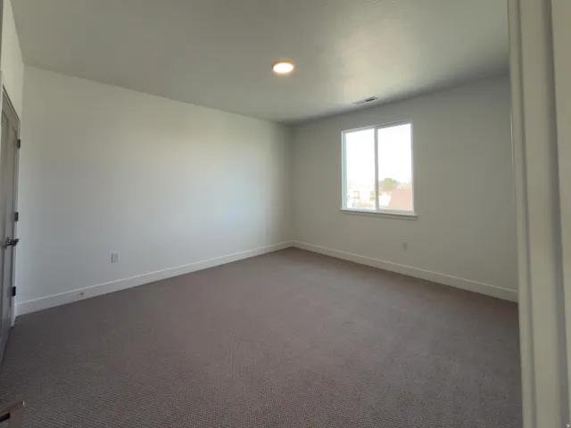 Spare room featuring baseboards and dark colored carpet