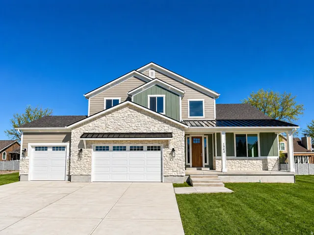 Craftsman inspired home featuring a standing seam roof, an attached garage, stone siding, a porch, and a front yard