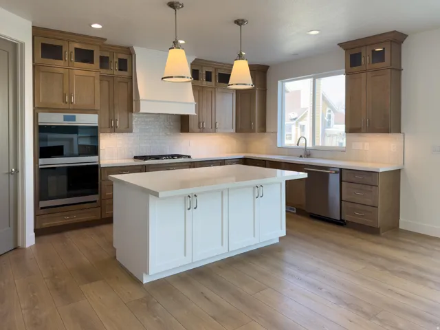 Kitchen featuring glass fronted cabinets, dual tone cabinetry, stainless steel appliances, hanging light fixtures, and a kitchen island