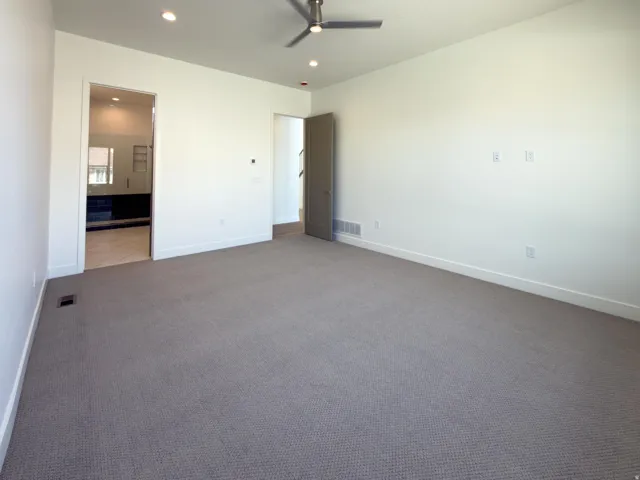 Unfurnished bedroom featuring recessed lighting, carpet, a ceiling fan, and ensuite bathroom