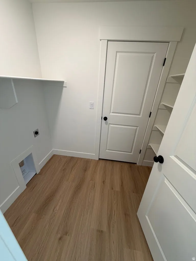 Laundry room featuring light wood-type flooring and hookup for an electric dryer