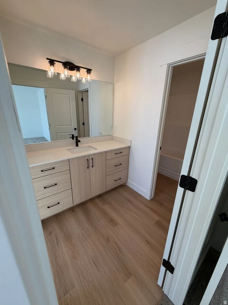 Bathroom featuring light wood-style floors, vanity, and a tub