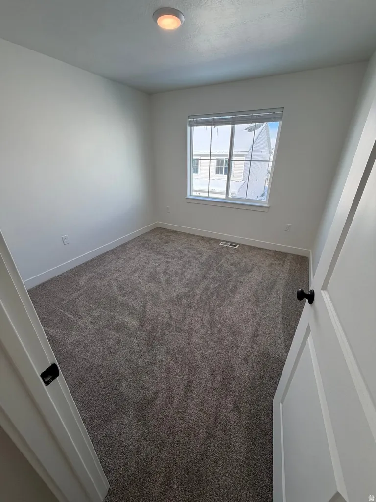 Empty room featuring dark colored carpet and baseboards