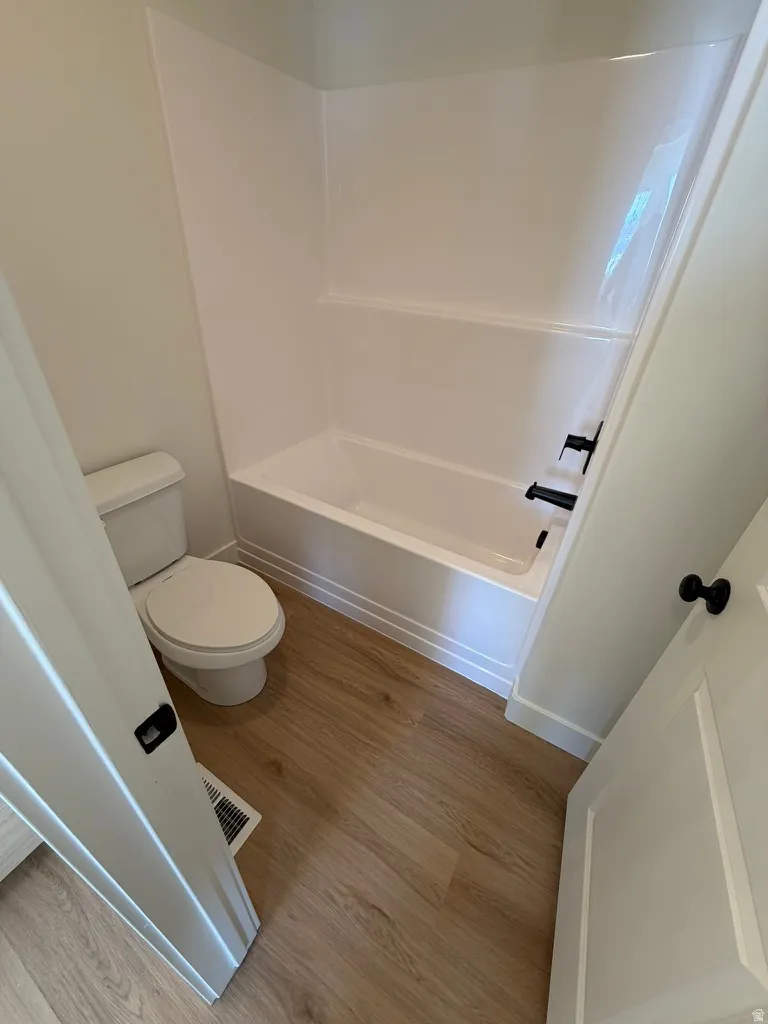 Full bath with light wood-type flooring and shower / washtub combination