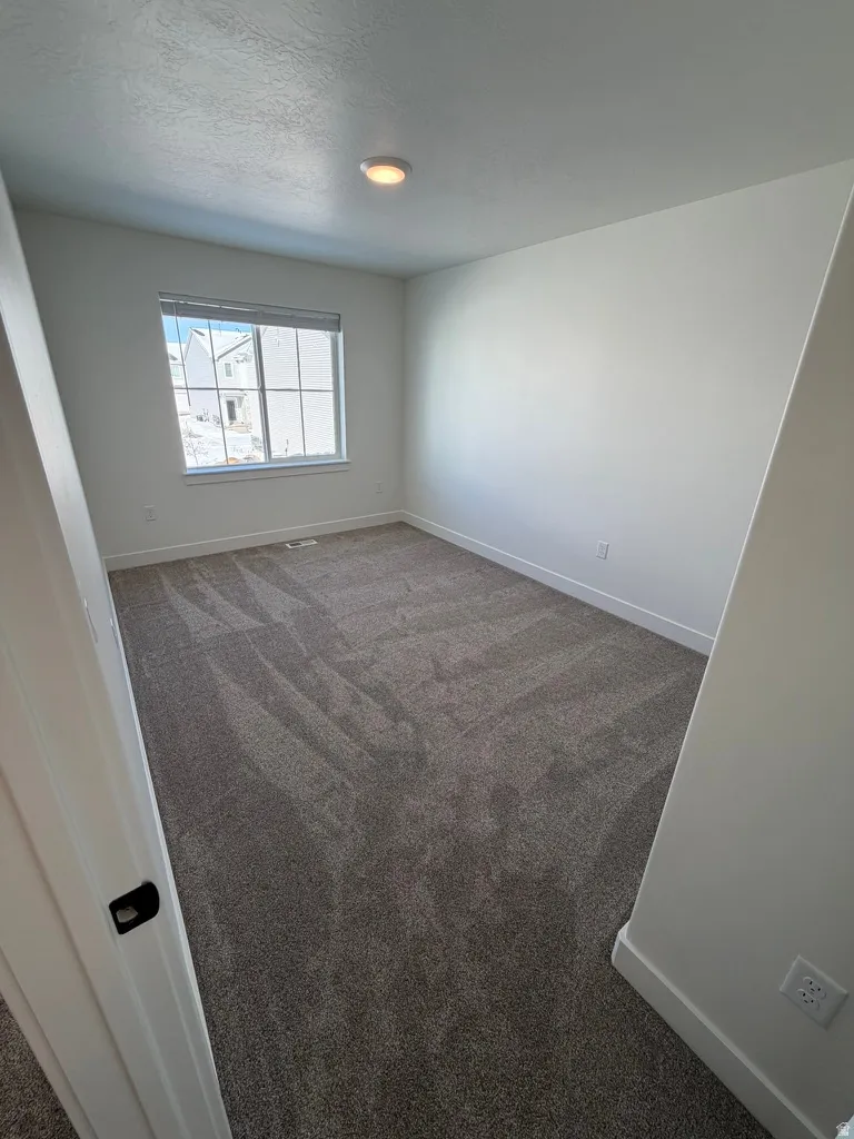 Spare room with dark colored carpet