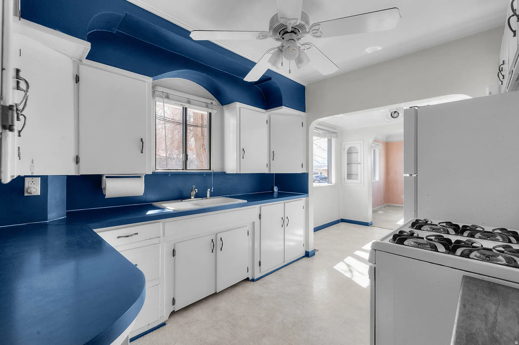 Kitchen featuring white appliances, a ceiling fan, and white cabinetry