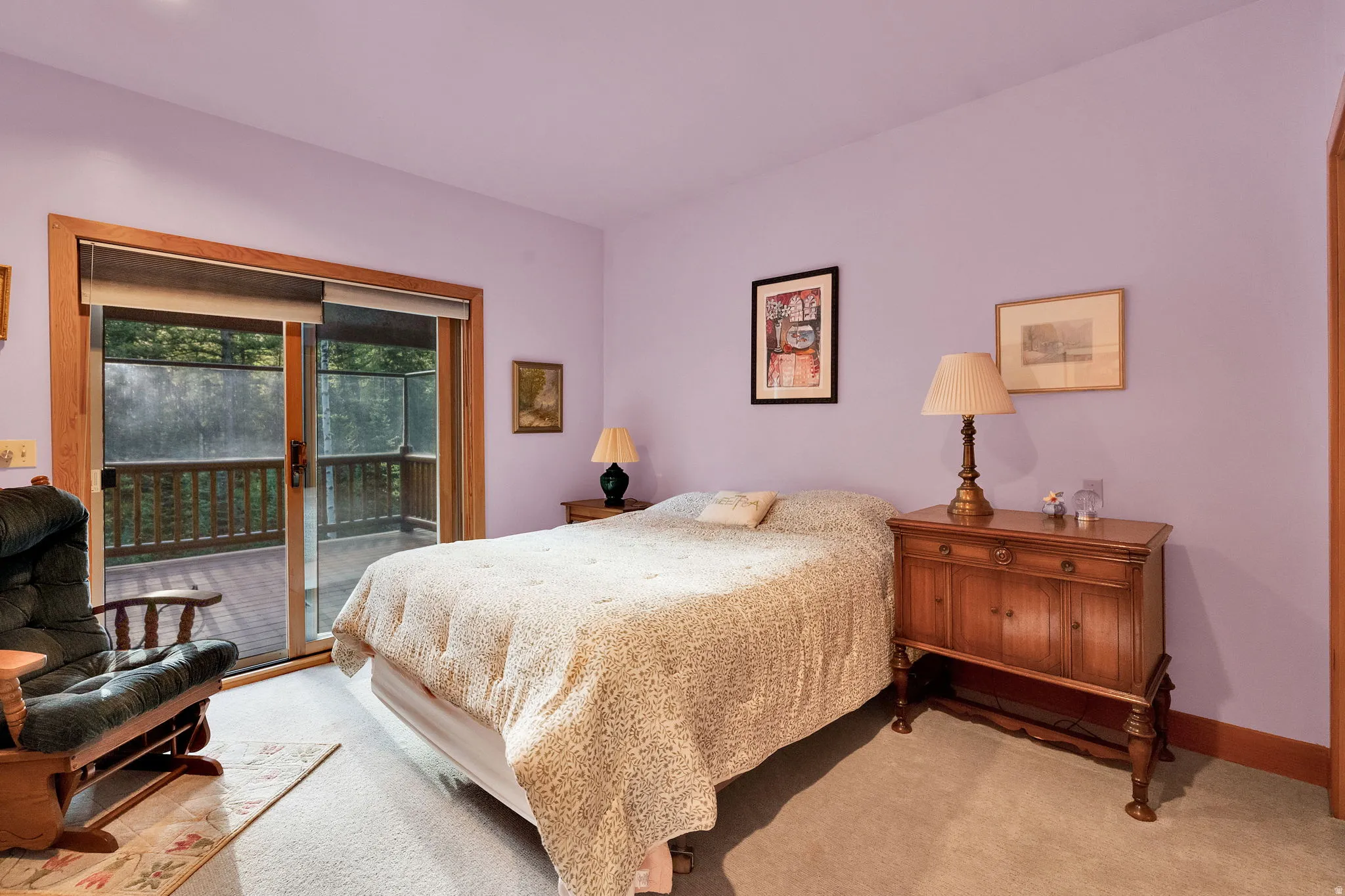 Carpeted room featuring a large sliding glass door with wood trim, opening to an exterior deck
