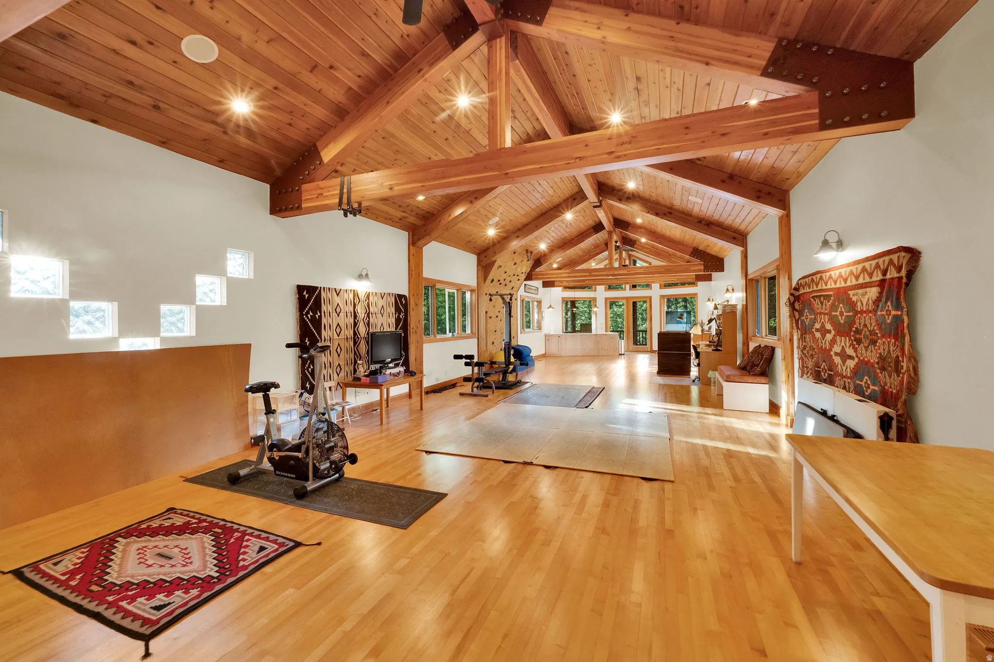 Spacious open-concept room featuring a vaulted wood-plank ceiling with exposed beams, recessed lighting, and wood-finish flooring